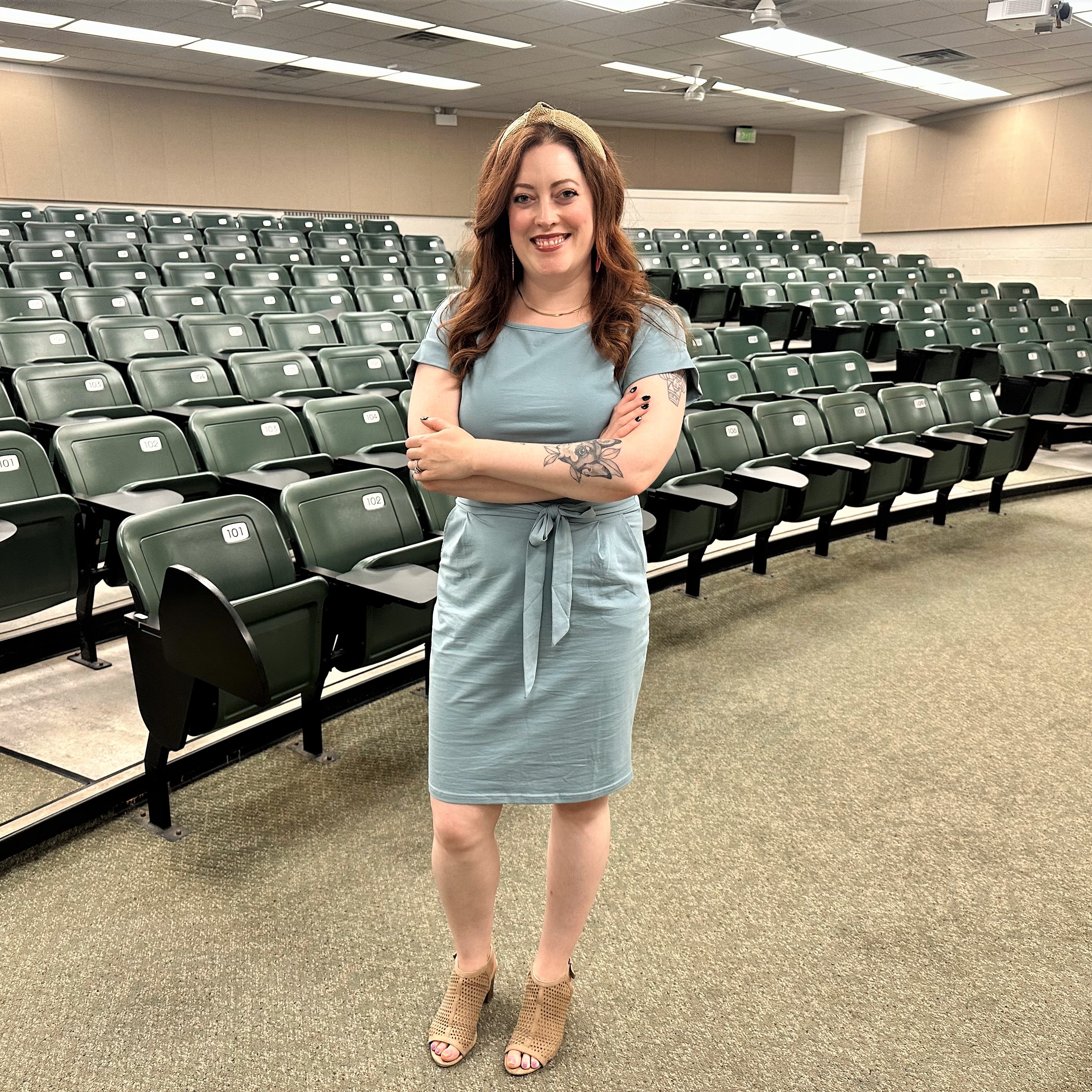 Dr. Clements stands in front of an empty classroom with her arms crossed.
